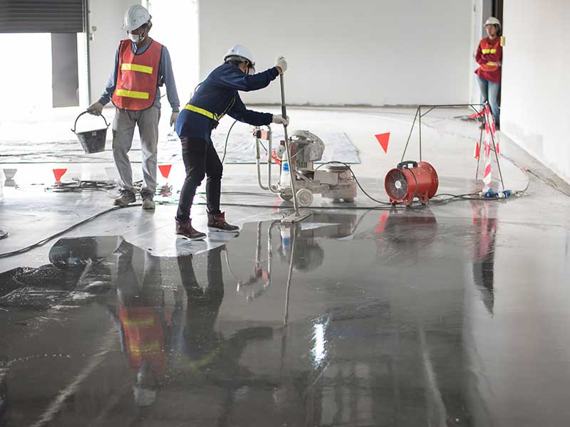 workers applying floor coating at construction site